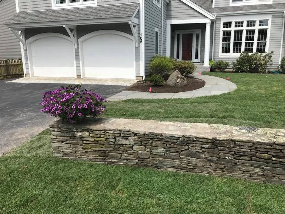 stone wall complimenting green front yard